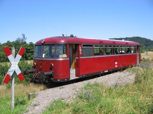Großaufnahme des roten Museumszugs der Hochwaldbahn. Links vorne in ein rot-weißes Andreaskreuz zu sehen