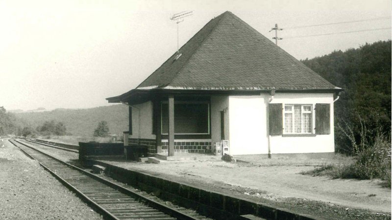 © Bernd Melcher, Sammlung Georg Dollwet alte schwarz-weiß Fotografie, die die Schienenführung und das Bahnhofsgebäude von Freisen aus dem Jahr 1978 zeigt.